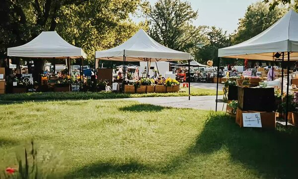 Outdoor market with white tents and greenery