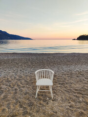 a lonely chair left in the middle of the beach on the coast of the sea
