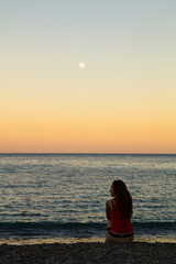 a lonely man sits on the seashore at sunset