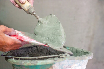 Hand holding cement mortar in tool
