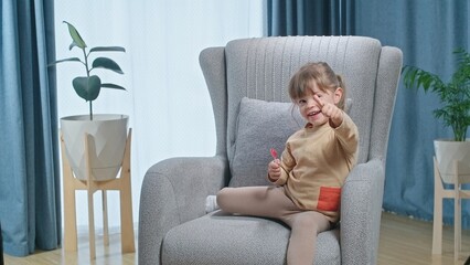 Cute laughing toddler girl liking lolipop and showing like and dislike sighn, concept of healthy...