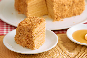 Layered honey cake slice with crumb coating on white plate