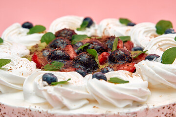 Delicious whipped cream berry cake with fresh strawberries and mint garnish on pink background