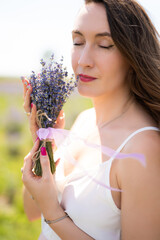 beautiful girl in a dress on a lavender field with a bouquet of flowers