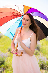 beautiful girl in a dress with on a lavender field with an umbrella