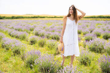 beautiful girl in a dress with a straw hat on a lavender field