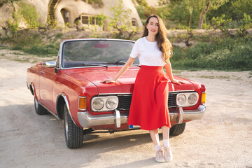 beautiful happy girl in a skirt posing near a retro car in the mountains of cappadocia