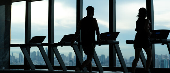 silhouette couple is running on Treadmills, exercisers and are checking how to exercise properly....