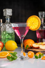 Cocktail glass with fruit drink forming a splash of fresh oranges and lemons with mint and bottles...