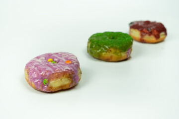 Three Colorful Donuts with Unique Frosting Arranged on a White Background