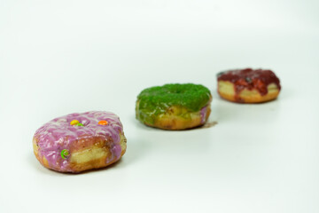 Three Colorful Donuts with Unique Frosting Arranged on a White Background
