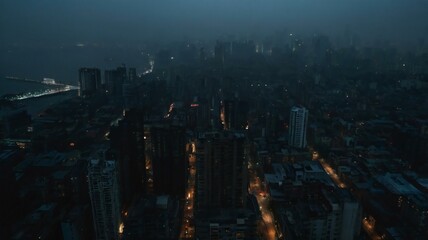 Obraz premium Night Cityscape: An aerial view of a city at night, showing a dense collection of buildings and streets, with scattered lights illuminating the darkness.