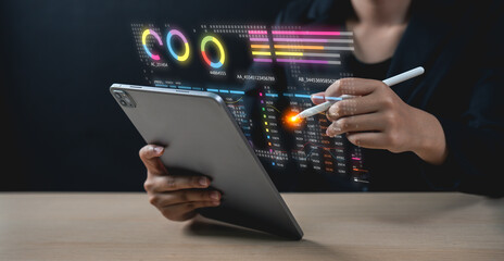 A person interacts with a tablet using a stylus, displaying futuristic digital charts and graphs...