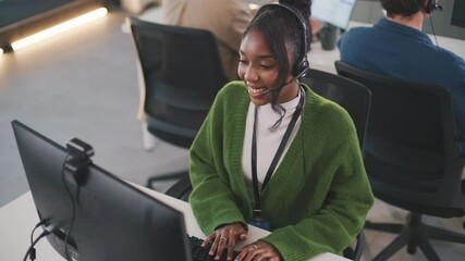 Smiling young african american professional customer support CRM Talking To Caller In Customer Services Department, Young Businesswoman Wearing Telephone Headset, Diverse call center team working - Powered by Adobe