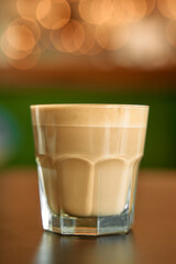 Rich creamy coffee in elegant glass with warm ambient bokeh lighting in cozy café setting