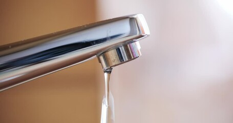 Dripping tap with water droplets inside apartment bathroom. Macro, close up, looking up shot, shallow depth of field, real time, no people - Powered by Adobe