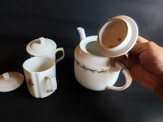 The hand holding the kettle and white ceramic cup