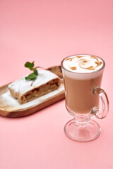 Cappuccino with latte art and apple strudel on pink background