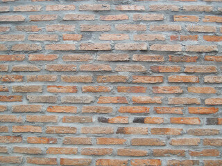An aged orange-brown brick wall showing signs of time and a rough cement surface, representing the strength and durability of building materials.