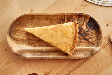 Golden apple pie slice on rustic wooden platter in cozy kitchen setting