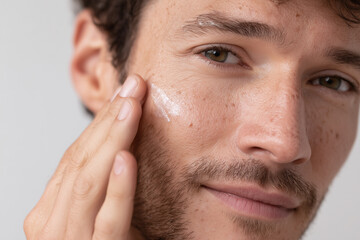 Obraz premium Man applying moisturizer on face close up with focus on hydration and skin care routine for healthy complexion and smooth skin texture