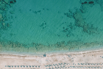 Drone photo of seaside landscape with crystal-clear water, underwater relief, white sand and beach umbrellas - perfect summer vacation