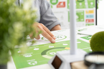 A diverse business team analyzing environmental charts and graphs in a collaborative meeting to create sustainable strategies in a modern office.