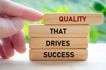 Quality that drives success text on wooden blocks being pushed forward symbolizes how excellence...