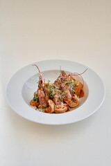 Gourmet seafood dish with shrimp and vegetables in white plate on table