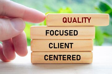Quality focused client centered text on wooden blocks held by hand showcases a dedication to understanding and serving clients
