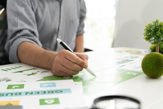 A diverse business team analyzing environmental charts and graphs in a collaborative meeting to create sustainable strategies in a modern office.