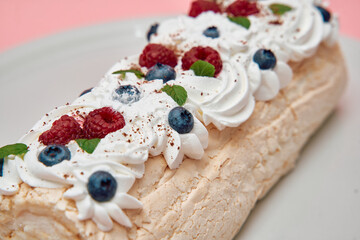Delectable meringue roll cake with whipped cream and fresh berries
