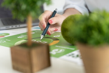 A diverse business team analyzing environmental charts and graphs in a collaborative meeting to create sustainable strategies in a modern office.