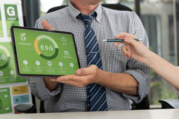 A diverse business team analyzing environmental charts and graphs in a collaborative meeting to create sustainable strategies in a modern office.