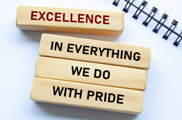 Excellence in everything we do with pride text on wooden blocks and notebook reflects unwavering quality and pride in every action