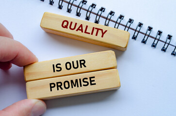 Quality Is Our Promise text on wooden blocks over notebook conveys commitment backed by meaningful intent