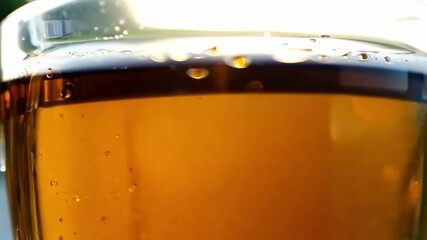 Golden beer glass with white foam head slowly settling and bubbling in bright studio lighting creating refreshing beverage scene with amber liquid and glass texture details - Powered by Adobe