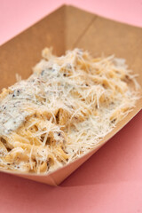 Creamy truffle tagliatelle with parmesan in eco-friendly box on pink surface