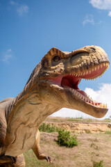 Huge Artificial dinosaur tyrannosaurus, close-up of dinosaur head against sky