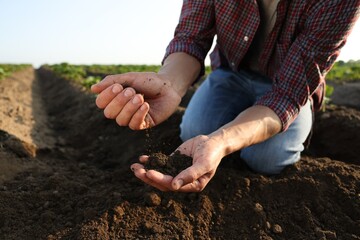 Man with pile of soil in field, closeup