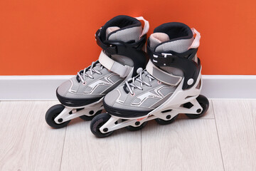 Pair of roller skates on floor near orange wall