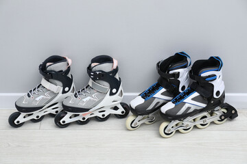 Pairs of roller skates on floor near white wall