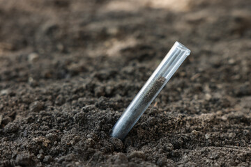 Test tube with soil sample outdoors, closeup. Space for text