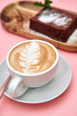 Latte art and chocolate cake on pink table