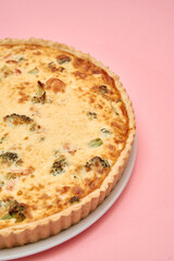 Delicious broccoli cheese quiche on pink background with golden crust