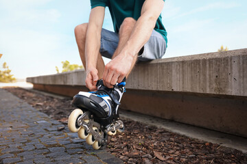 Man putting on roller skates outdoors, closeup