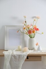 Bouquet of beautiful poppy flowers, frame and burning candles on table indoors
