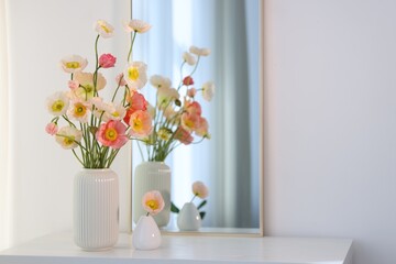 Beautiful poppy flowers and mirror on table indoors. Space for text