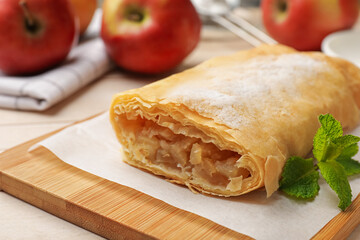 Tasty apple strudel with powdered sugar, mint and fruits on table, closeup