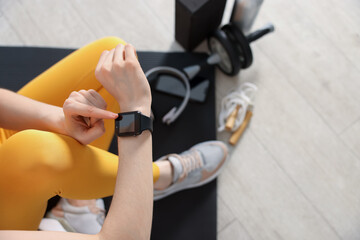 Woman checking fitness tracker during training indoors, above view. Space for text